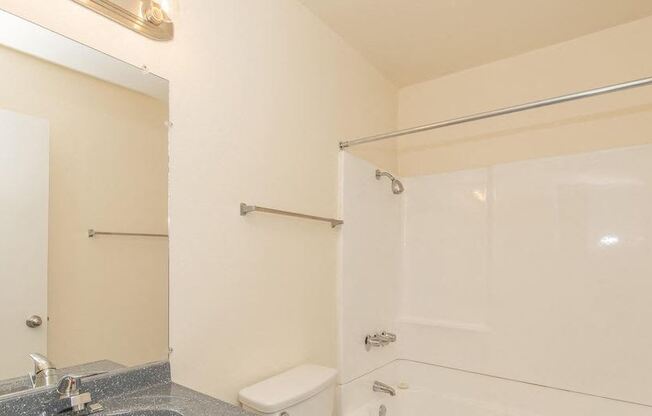 a white bathroom with a shower and a toilet at Villa La Paz Apartments, Bellflower, CA