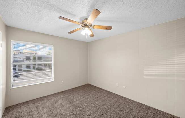 an empty bedroom with a ceiling fan and a window at Brookside Apartments, Hewitt, TX