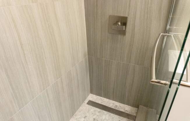 a close up of a marble shower with a glass door