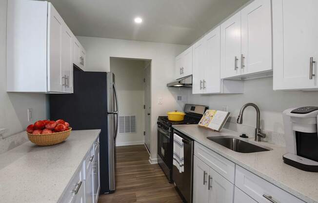 A kitchen with white cabinets and a black refrigerator.