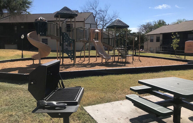 A playground with a slide, swings, and picnic tables.