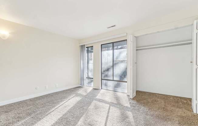 A room with a carpeted floor and sliding glass doors.