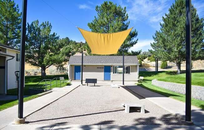 Covered game area at Kirkwood Meadows Apartments in Pocatello, ID. Green grass area with Corn Hole game.