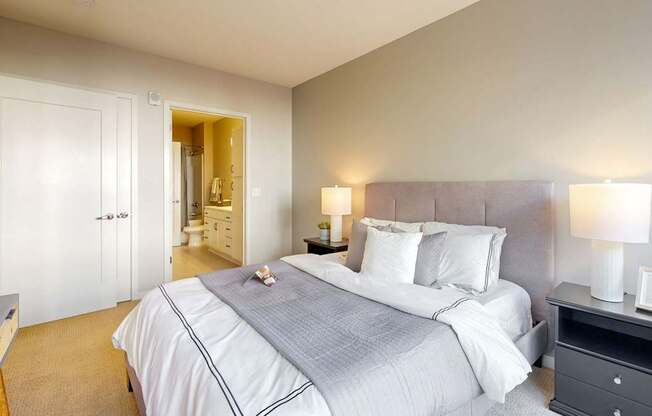 A bedroom with a large bed and a nightstand with a lamp.