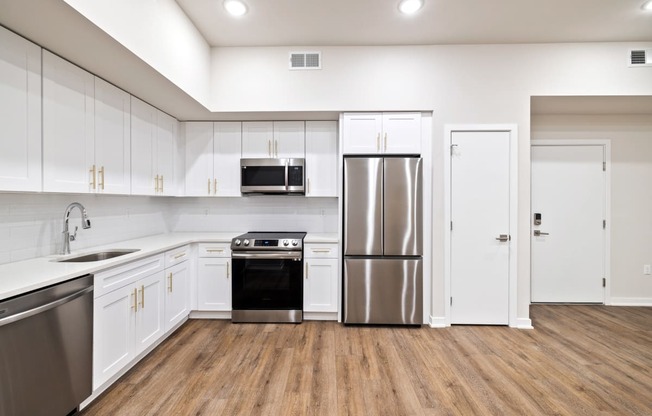 an empty kitchen with white cabinets and stainless steel appliances