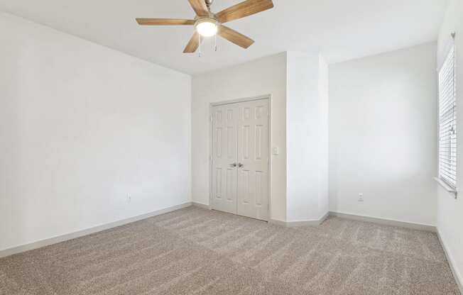 an empty living room with white walls and a ceiling fan