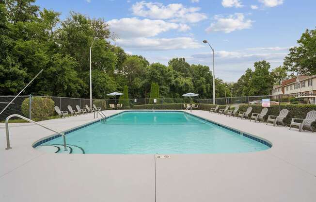 A large swimming pool surrounded by trees and lounge chairs.