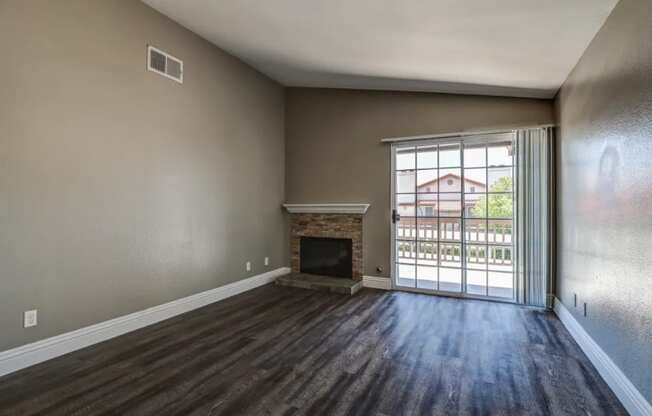 an empty living room with a fireplace and a sliding glass door