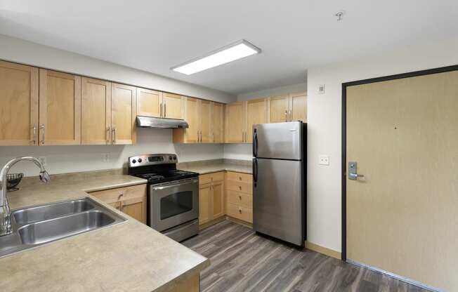 a kitchen with wooden cabinets and stainless steel appliances at Villaggio Apartment Homes, WA 98402