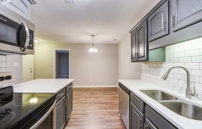 an empty kitchen with stainless steel appliances and white counter tops