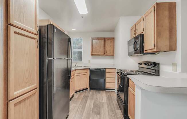 A kitchen with wooden cabinets and black appliances.