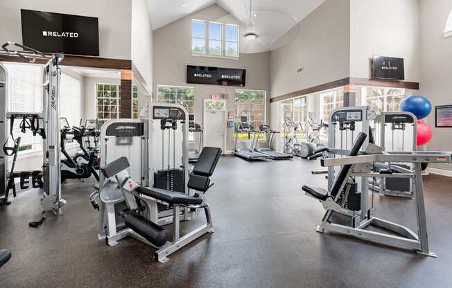 a gym with cardio equipment and weights in a building with a window