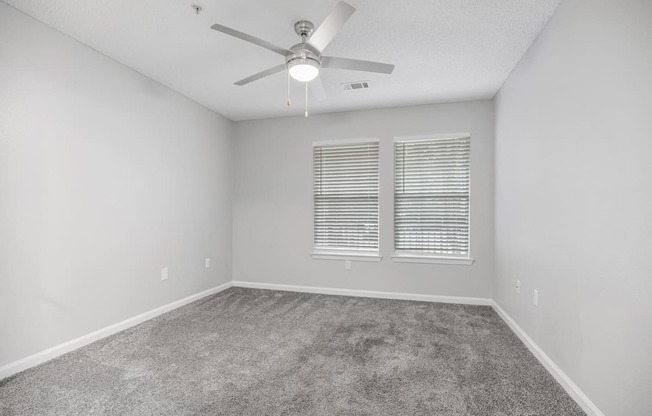 an empty room with a ceiling fan and a window