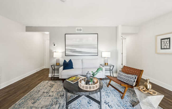 A living room with a white couch, a coffee table, and a painting on the wall.