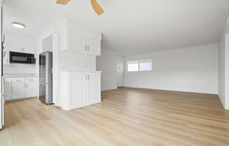 A spacious kitchen with white cabinets and a wooden floor.