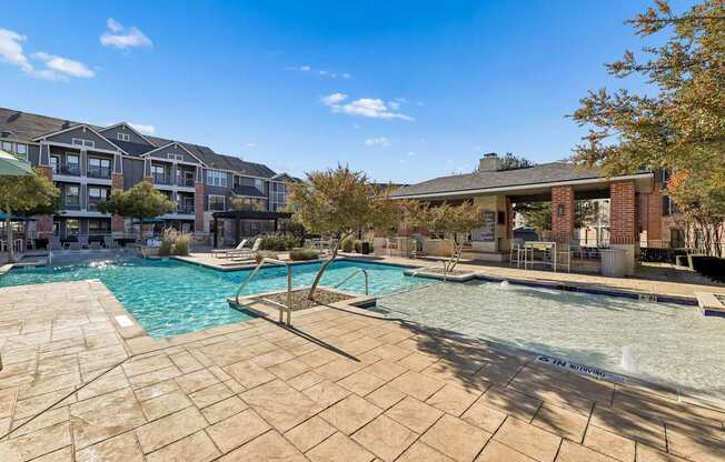 A large outdoor swimming pool surrounded by a stone patio.