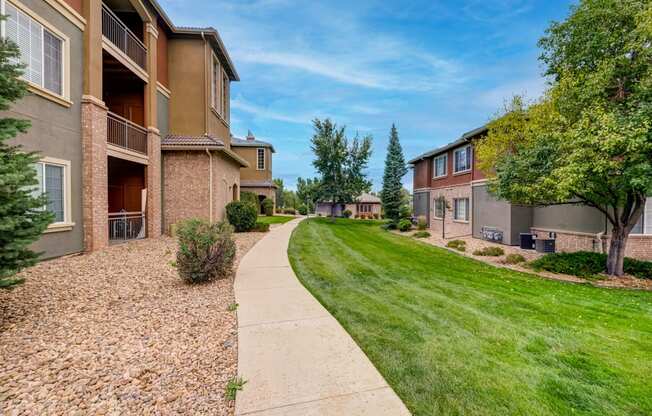 a walkway between two apartment buildings with grass and trees