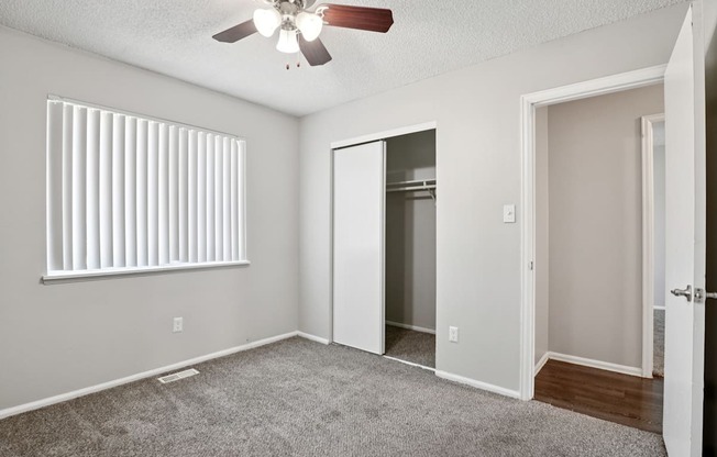 A room with a ceiling fan and a window with blinds.
