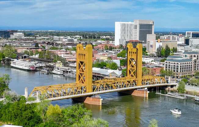 A yellow bridge spans a river in a city.