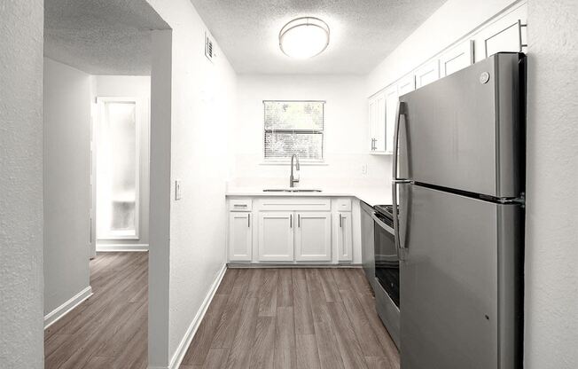 an empty kitchen with stainless steel appliances and white cabinets