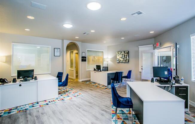 a room with desks and chairs and a hallway in the background