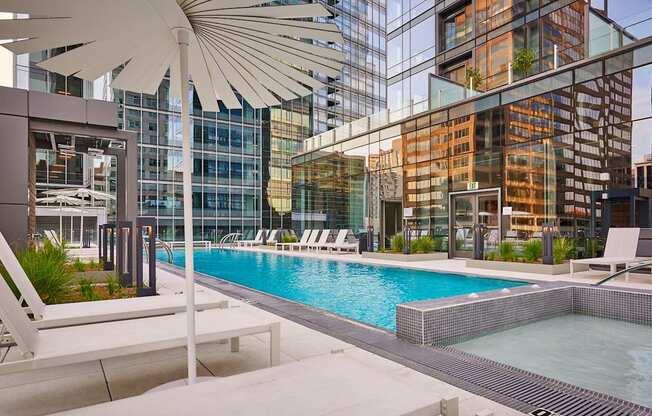 A pool area with a white umbrella and lounge chairs.