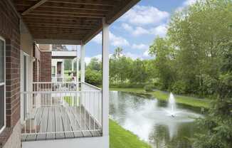 a porch overlooking a pond with a fountain