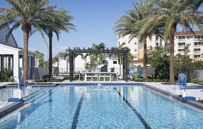 a large swimming pool with a pergola and palm trees in the background at Odyssey, Fort Myers, Florida