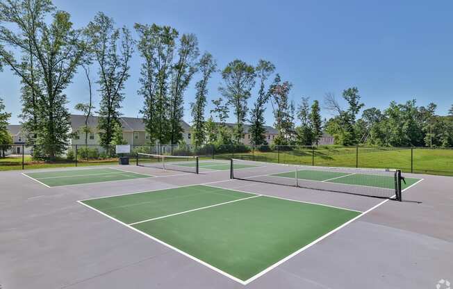 A tennis court surrounded by trees and a fence.
