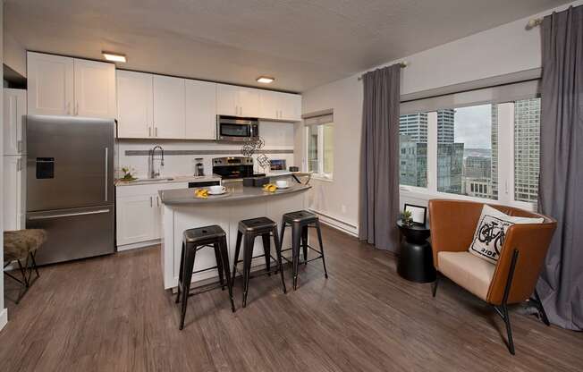 A modern kitchen with a refrigerator, stove, and bar stools.