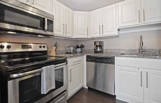 Kitchen with Granite countertops, Stainless Steel Appliances, Dishwasher, cabinet space, and hardwood floors at Bancroft Apartments in Saginaw, MI