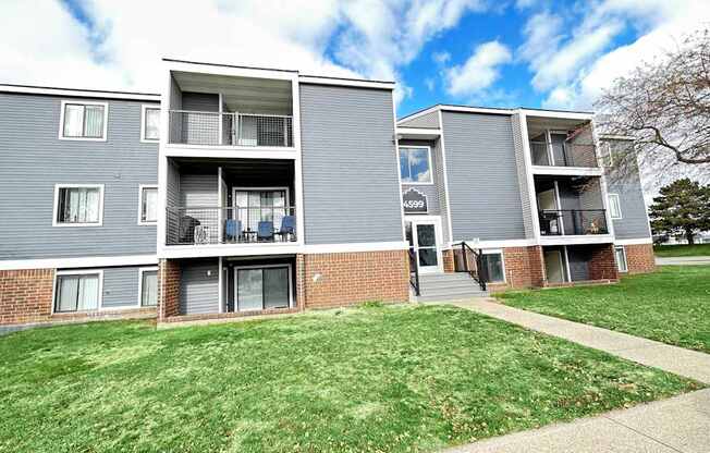 a view of an apartment building with a sidewalk and grass