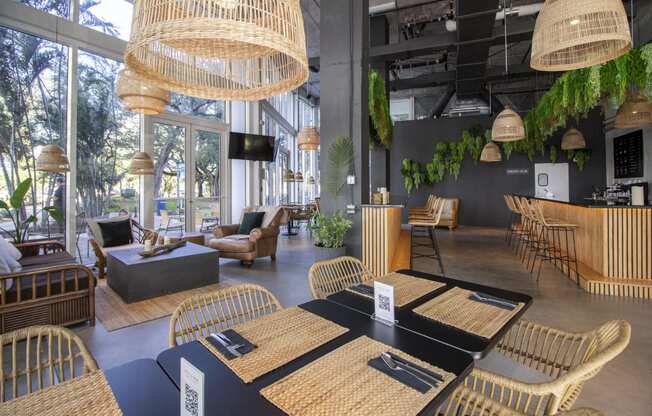 a restaurant with wicker tables and chairs and large windows