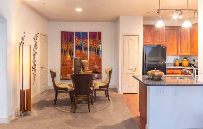 a kitchen and dining room with a table and chairs and a painting on the wall