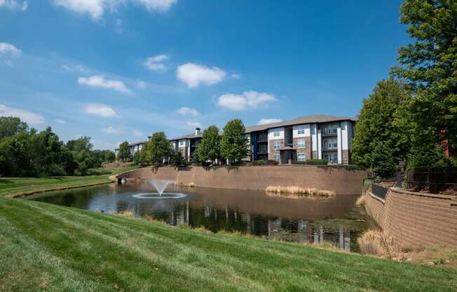 a pond with a fountain in front of a building
