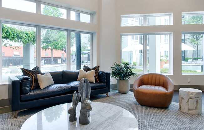 A living room with a black couch and a round orange chair.