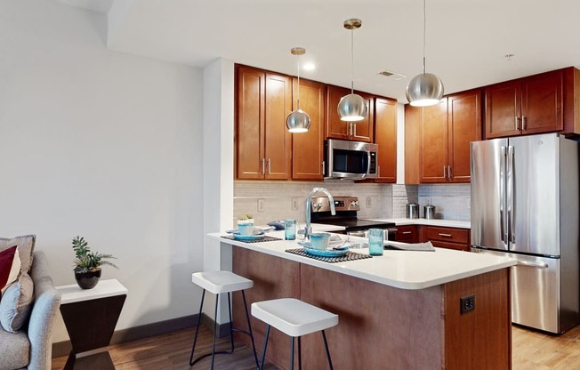Kitchen with peninsula countertop, tile backsplash, and modern appliances in a 1 bedroom floor plan at Midtown Crossing Apartments Omaha