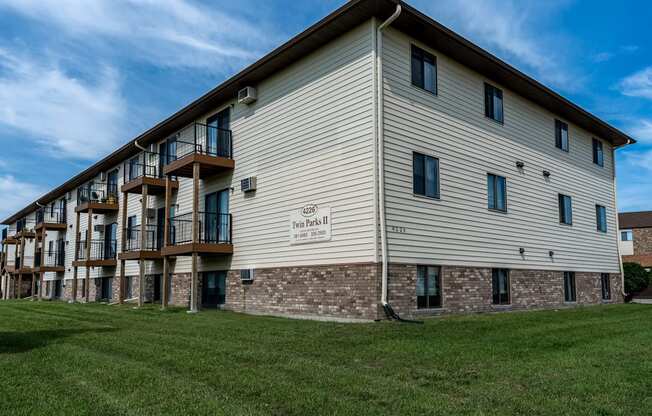 The exterior of a three level apartment building with a grass area out front