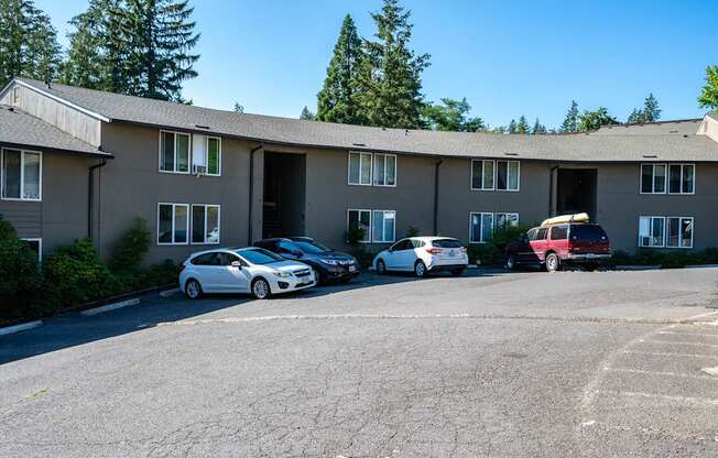 A parking lot in front of a building with cars parked.