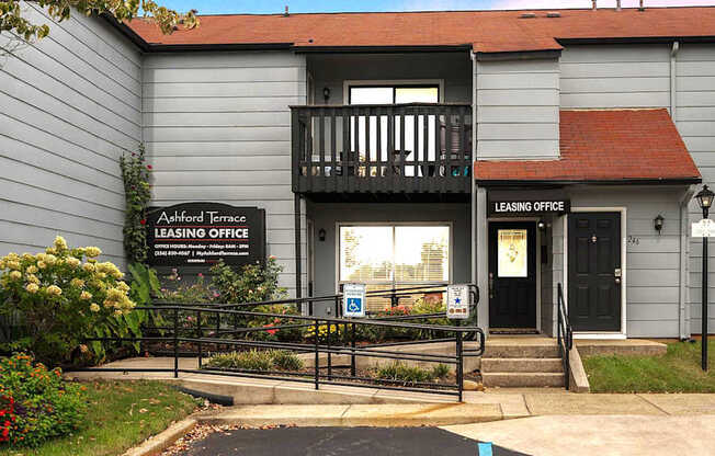 A grey building with a black sign that says Leasing Office.