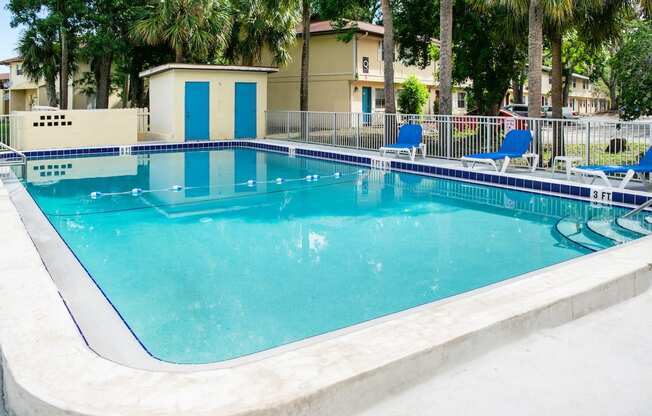 a large swimming pool with blue chairs around it