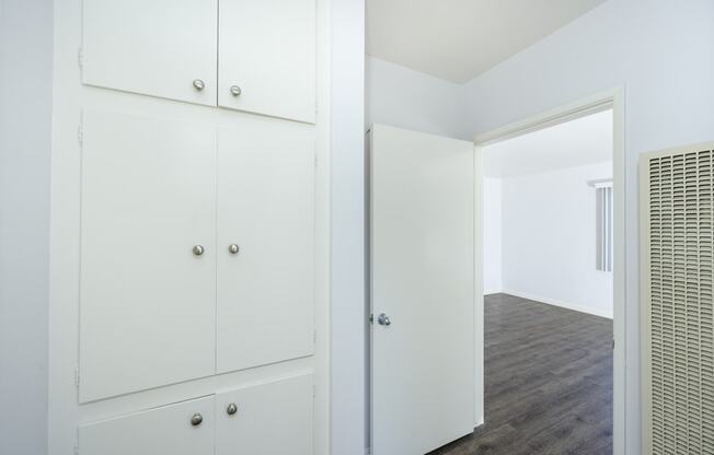 a bedroom with white cabinets and a door to a closet