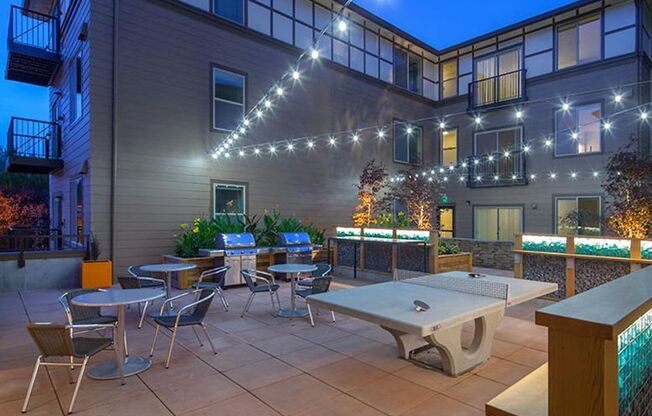 an outdoor patio with tables and chairs at night