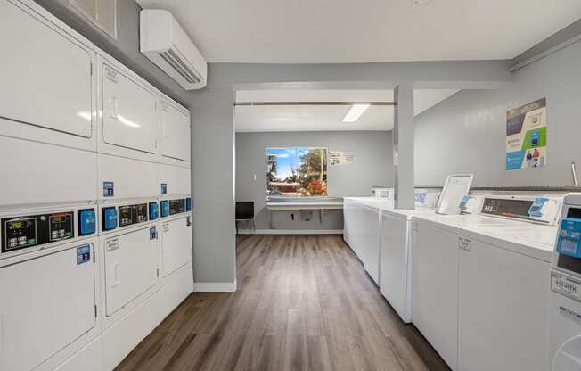 a laundry room with washes and dryers and a counter with a window