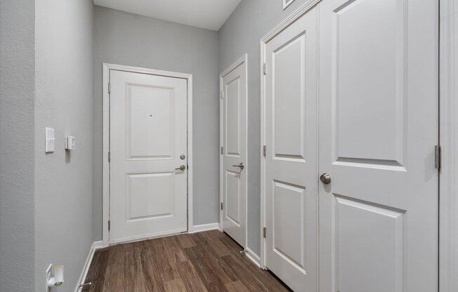 an empty room with white doors and wood floors