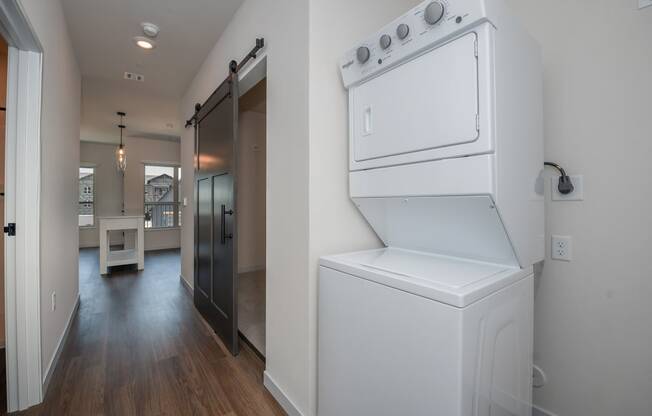a laundry room with a washer and dryer and a hallway with a door at The Crossings at Windsong, Prescott Valley, Arizona