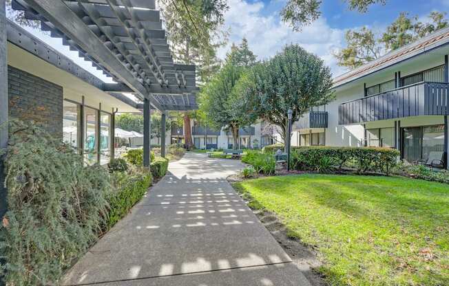 a pathway between two buildings with grass and trees