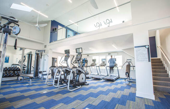 a view of the gym with cardio equipment and a staircase in the background