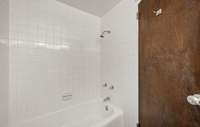a white bathroom with a white tub and a wooden door