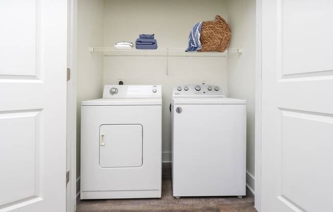 a small laundry room with a washer and dryer and a shelf above the